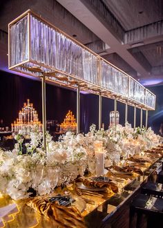 a long table is set up with white flowers and candles for an elegant dinner party