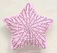 a close up of a pink and black star ornament on a white surface