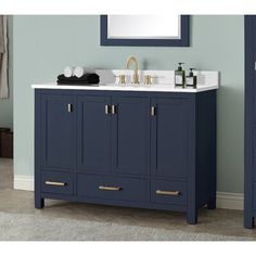 a bathroom vanity with two drawers and a mirror above it, in front of a blue wall