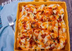 a yellow casserole dish filled with cheese and bacon on a blue table cloth