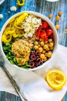 a white bowl filled with chickpeas, olives, tomatoes and other vegetables