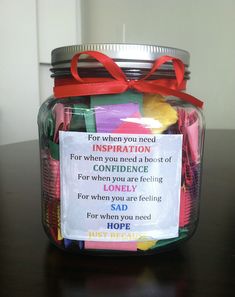 a jar filled with lots of candy sitting on top of a wooden table next to a sign