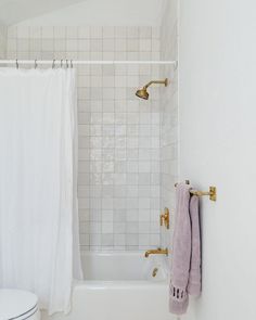 a bathroom with white tile and gold fixtures