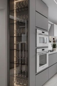 a kitchen with an oven, microwave and wine glasses on the shelves in front of it