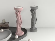 two candles and some statues on a table