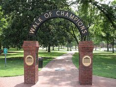 a brick arch with the words walk of champions on it in front of some trees