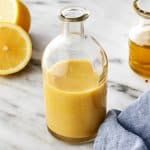 a glass bottle filled with liquid next to sliced lemons