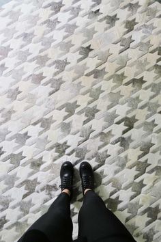 a person wearing black shoes standing on top of a white and gray carpeted floor