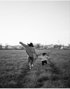 two children running in a field holding hands