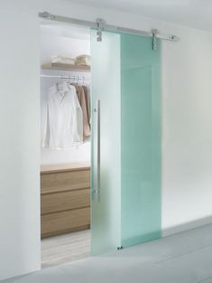 an open closet with glass doors and clothes on hangers