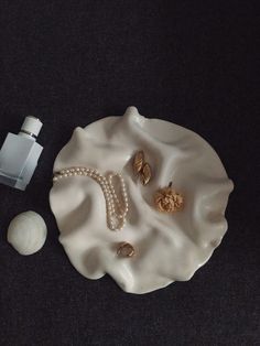 shells and pearls on a white plate next to an empty bottle