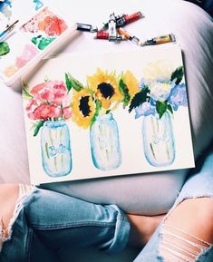 a woman laying on top of a white couch next to a vase filled with sunflowers