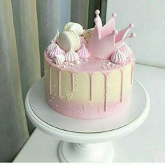 a pink and white cake with icing on it sitting on top of a table