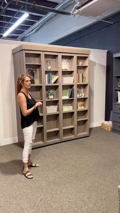 a woman standing in front of a bookcase with shelves on the wall behind her