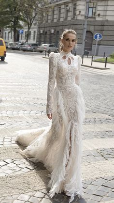 a woman is walking down the street wearing a white dress with long sleeves and high slits