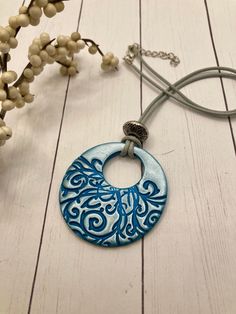 a blue and white circular pendant sitting on top of a wooden table next to a plant