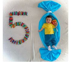 a baby laying on top of a blue blanket next to the numbers 5 and 6