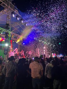 the crowd is watching fireworks and confetti being thrown into the air at an outdoor concert