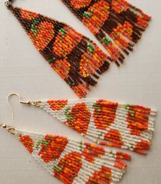 three pieces of beaded jewelry are laying on a white surface, one is orange and the other is brown