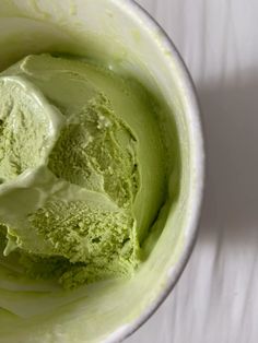 a bowl filled with green ice cream on top of a white tablecloth covered table