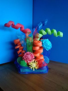 a blue vase filled with lots of different colored flowers on top of a wooden table