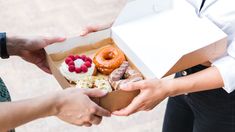 two people are handing out doughnuts to each other