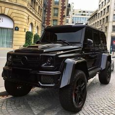 a black mercedes g - class is parked on the street