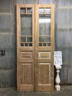 an old wooden door sitting in front of a metal building with a sign on it