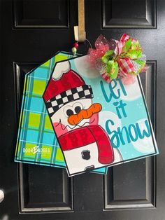 a door hanger that says let it snow with a cartoon character hanging from the front