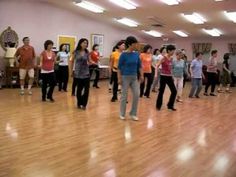 a group of people standing on top of a wooden floor next to each other in a room