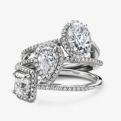 three pieces of engagement and wedding rings with diamonds on each band, set against a white background