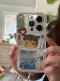 a person holding up a cell phone case with stickers on it