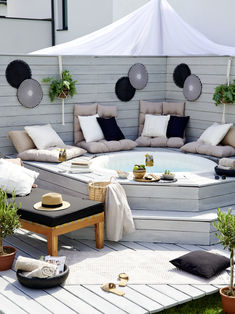 an outdoor hot tub surrounded by plants and pillows