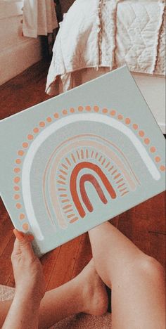 a person laying on the floor holding up a box with an image of a rainbow in it