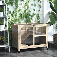 a small wooden cage sitting on top of a tiled floor next to a green plant