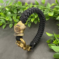 A handmade bracelet in 550 paracord featuring a brass coloured metal shackle and a knight's helmet bead. All of my Paracord is genuine, US manufactured, military grade (100% nylon) cord. This ensures all of my products are of the highest quality and standard. Shackle has 3 different holes to adjust the size.. PLEASE NOTE: The exact number of spacer beads will vary depending on wrist size. The bracelet will always feature the Templar knight helmet and 2 shield beads either side. For sizing please measure your wrist without any gaps or slack and select this as the size. I will add the extra length to the bracelet to ensure it fits. For other sizes and colours please get in touch. Knight's Helmet, Knights Templar Paracord Bracelets, Marine Corps Paracord Bracelet, Handmade Black Paracord Braided Bracelet, Ranger Beads Paracord, Adjustable Black Paracord Braided Bracelet, Templar Knight, Knight Helmet, Knights Helmet