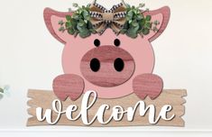 a wooden sign that says welcome with a pig wearing a wreath on it's head