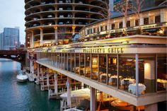 a restaurant on the side of a river in front of a large building with balconies