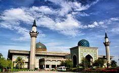 an ornate building with two minalis on the top and one in the middle, against a blue sky filled with clouds