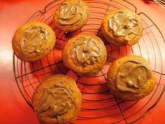 six cookies with peanut butter on top are cooling on a wire rack next to an orange bowl