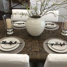 the table is set with white plates and place settings