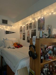 a bed with headphones and pictures on the wall above it in a dorm room