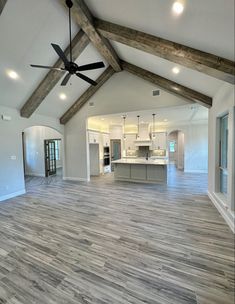 an empty living room with wood flooring and ceiling fan in the middle of it