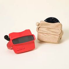 two small wooden objects sitting next to each other on a white surface, one red and the other black