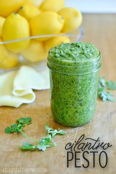 a green smoothie in a jar next to some lemons and parsley on the table