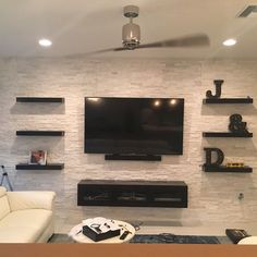 a living room with shelves and a flat screen tv mounted on the wall above it