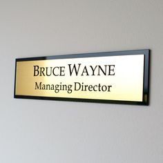 a gold and black sign that says bruce wayne managing director on the side of a wall