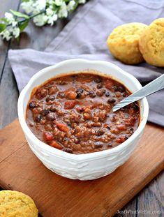 a white bowl filled with chili next to cookies on top of a wooden cutting board