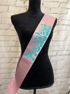 a black mannequin with a pink and blue sash on it