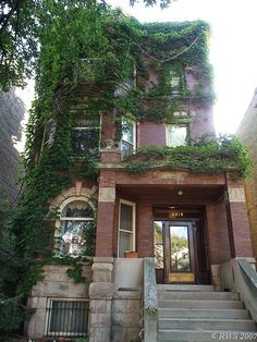 an old brick building with ivy growing on it's side and stairs leading up to the front door